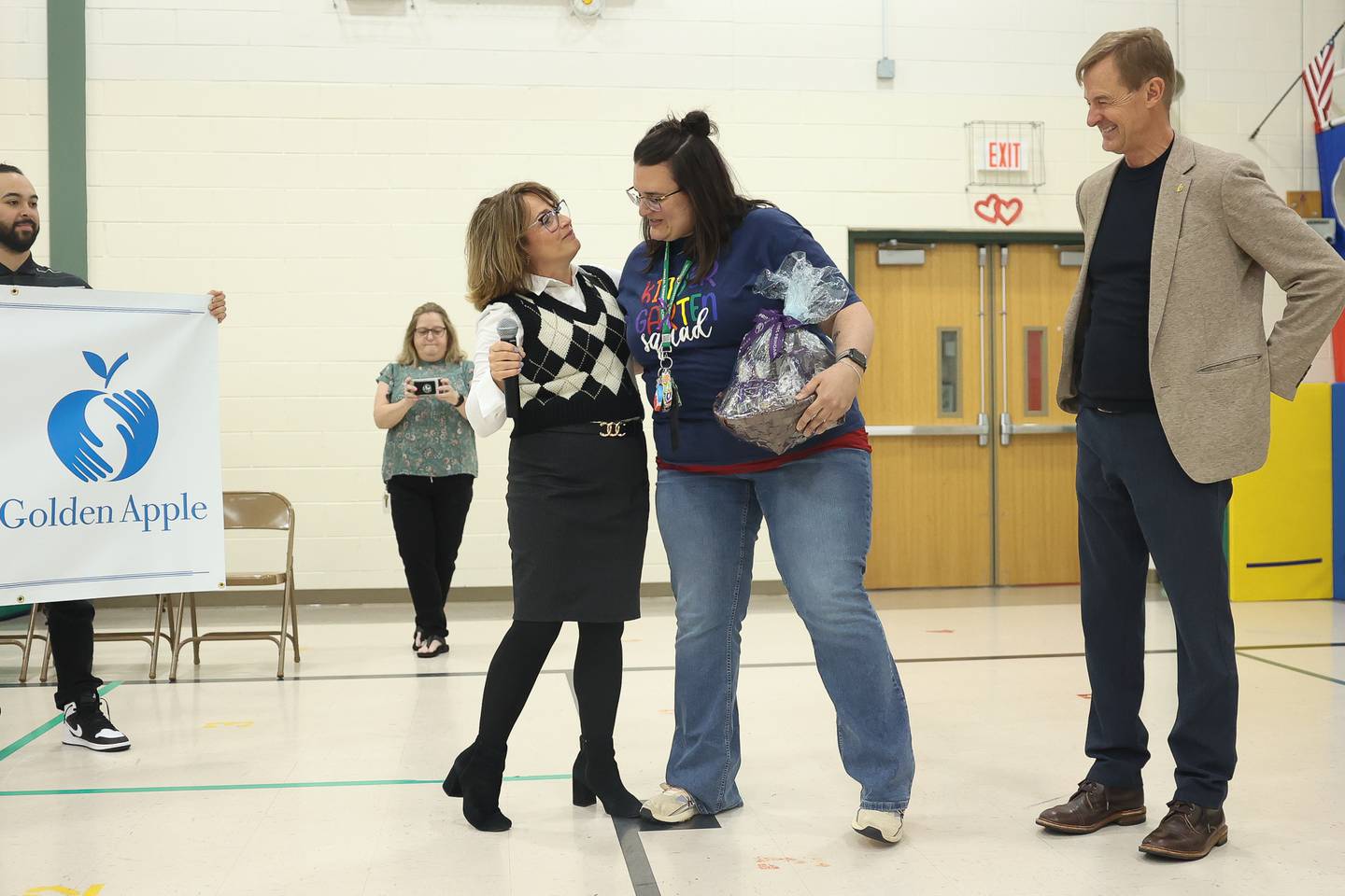 Illinois State Senator, District 49, Meg Loughran Cappel congratulates, left, Central Elementary School teacher Alyssa Milano as Alan Mather, President of the Golden Apple Foundation, watches during the Golden Apple Award for Excellence in Teaching ceremony on Monday, April 29, 2024 in Plainfield.