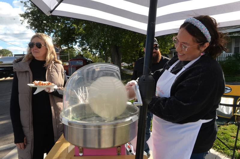 Chelsea Hamilton of Cotton Candy Smiles spins a pumpkin flavored treat for Kate Kastanova of Oregon during Autumn on Parade on Saturday, Oct. 7, 2023. The cotton candy maker was one of the vendors in the Fun Zone for kids.