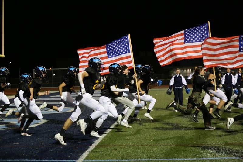 Members of the Downers Grove South football team take the field Oct. 6 wearing alternate U.S. Army jerseys for a game designed to pay tribute to veterans, active service members and first responders. The team was led onto the field by left tackle Joshua Manecke who has committed to play football at West Point.