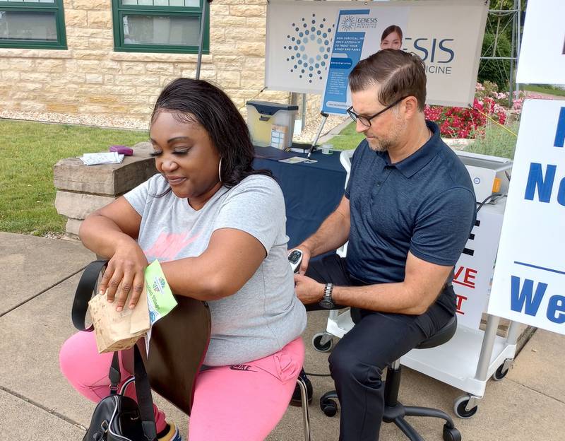 Chiropractor Nathan Conroy demonstrates shockwave therapy on Jackie Wright's lower back at the WellBatavia Festival Saturday at Batavia City Hall. Conroy, owner of Genesis Integrative Medicine, uses the therapy to treat pain in a non-invasive way.