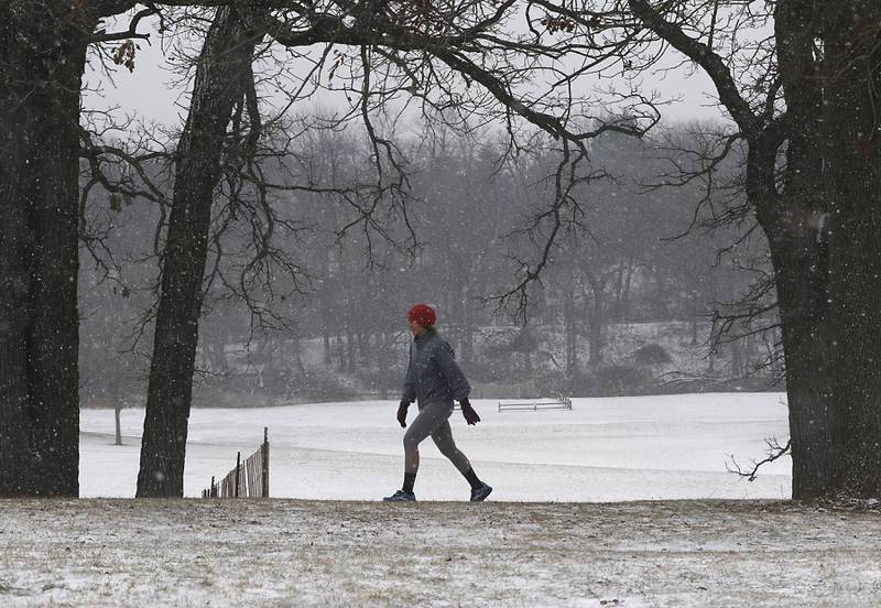 A woman walks in Veteran Acres Park on Thursday, Dec. 22, 2022, just as it starts to snow in Crystal Lake.