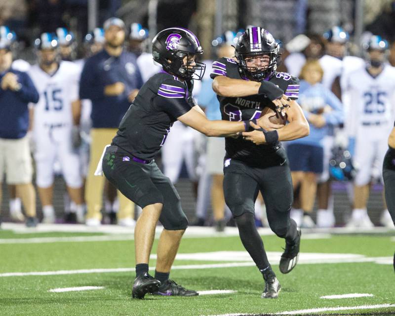 Downers Grove North's Owen Lansu hands the ball off to Downers Grove North's Jake Gregorio against Downers Grove South on Friday Sept. 6,2024 in Downers Grove.