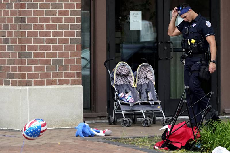 A police officer reacts as he walks in downtown Highland Park, a suburb of Chicago, Monday, July 4, 2022, where a mass shooting took place at a Highland Park Fourth of July parade. (AP Photo/Nam Y. Huh)