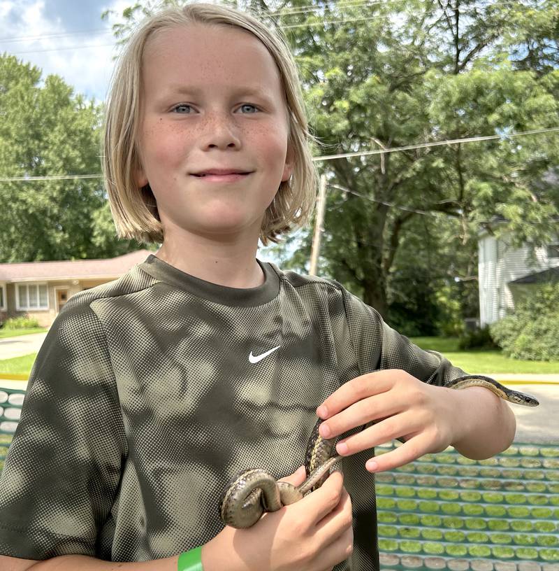 Paxton Erdmier, 10, of Rockford, holds a snake at Kriss' Funny Farm & Wedding Barn's petting zooe during German Valley Days on Saturday, July 20, 2024.