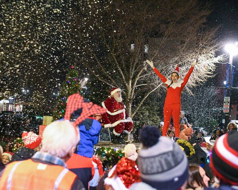 Community members gather around Santa and one of his elves as they stop in front of the Egyptian Theatre in downtown DeKalb to help turn on the tree lights during the DeKalb Chamber of Commerce's annual Lights on Lincoln and Santa Comes to Town event held in downtown DeKalb on Thursday, Nov. 30, 2023.