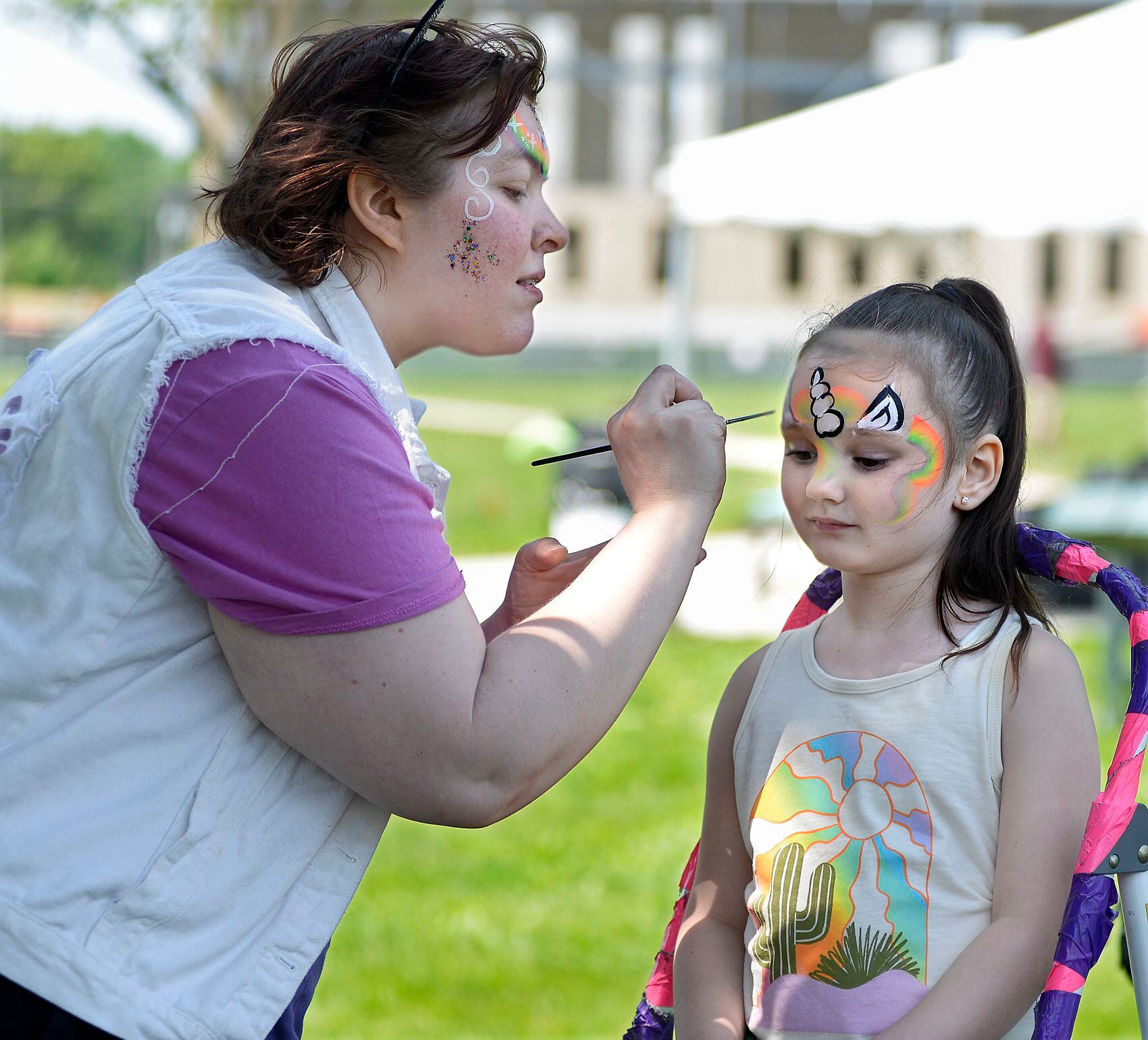 During the Kites In Flight Fest at Riverfront Park in Ottawa on Saturday, May 20, 2023, Emery Sibigtroth has her face decorated by Coleen Cherry.