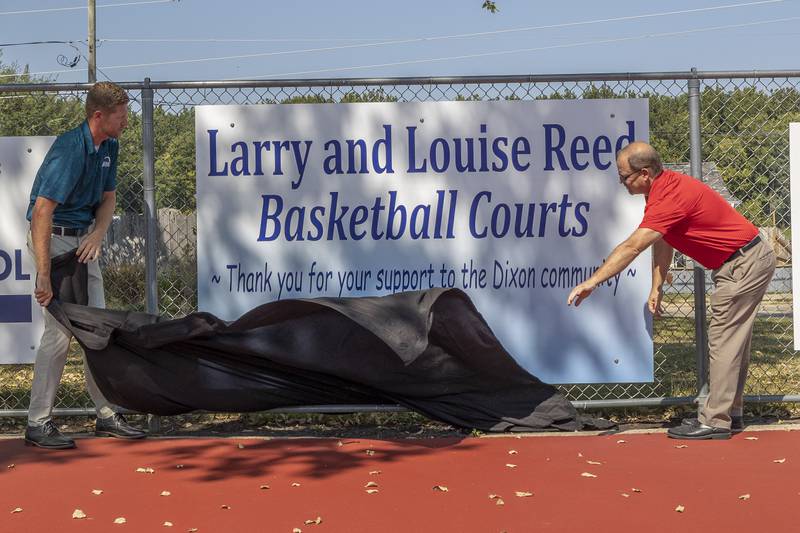 Seth Nicklaus (left) and Duane Long unveil a sign for the Larry and Louise Reed Basketball Courts Tuesday, Sept. 17, 2024, at Vaile Park in Dixon.