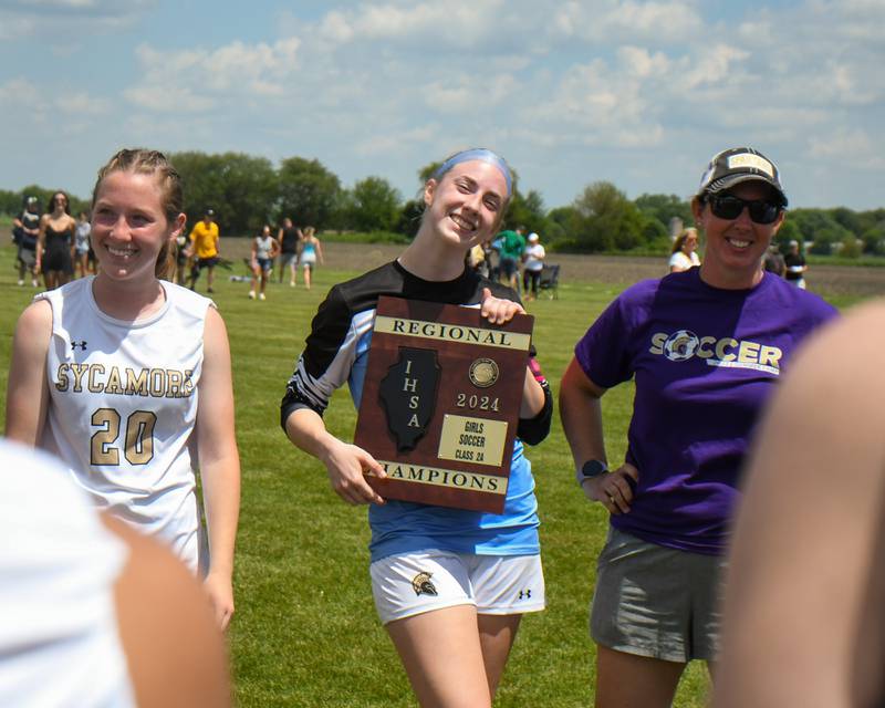 Sycamore's Tayla Brannstrom, center, poses with the regional title plaque after making saves in the goal during penalty kicks against Kaneland on Saturday May 18, 2024, held at Kaneland High School.