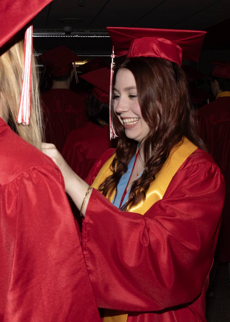 Lily Gardner adjusts a classmates gown Sunday, May 19, 2024, prior to walking into the Streator High School's graduation ceremony in the school gym.