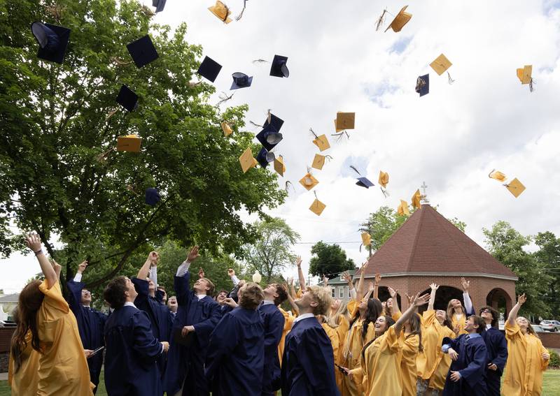 Members of Marquette Academy High School's Class of 2024 gather in the school's courtyard and toss their caps toward the sky in celebration of their graduation Sunday, May 26, 2024.
