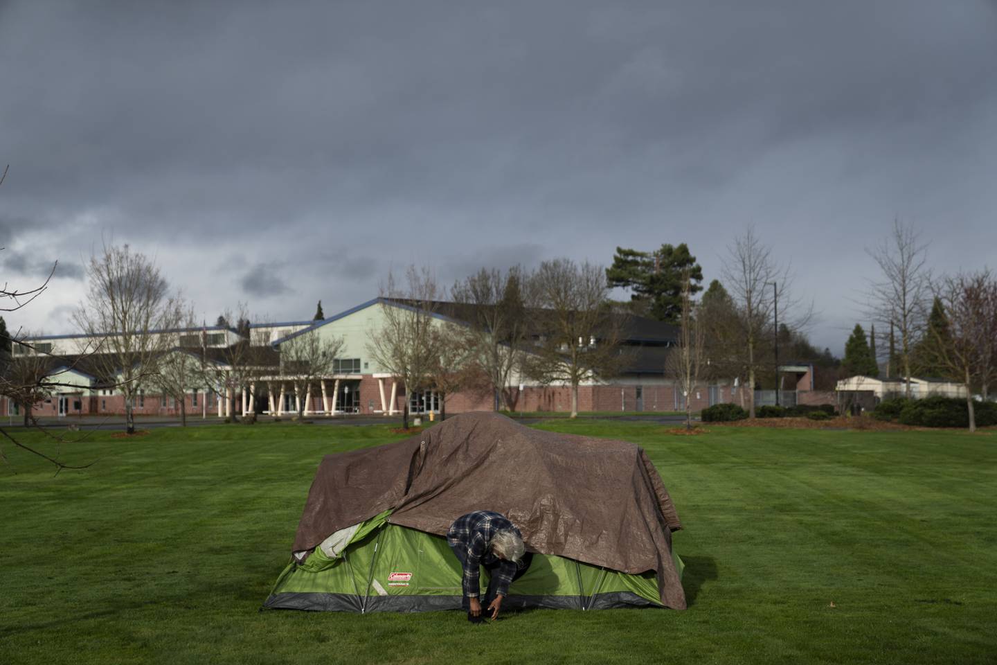 A homeless man adjusts his shoe at Fruitdale Park, Saturday, March 23, 2024. Sterling is considering a ban on homeless camping in public spaces.