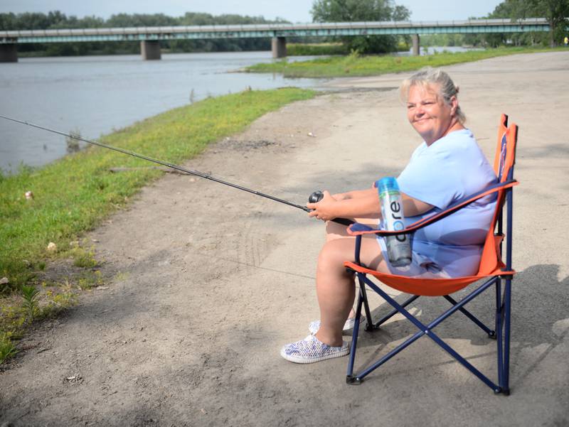 Chrystal Ferrari of Rochelle sits on her Bears chair as she fishes in the Rock River at the Glenn Miller Marina near Erie on Saturday, June 22, 2024..