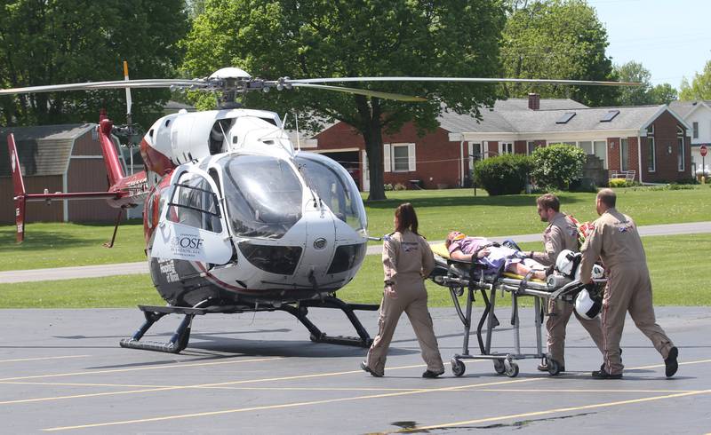 Putnam County High School student Anna Sandburg is carried to a medical helicopter by OSF Lifeflight crew during a "mock prom" scene through the Putnam County Corner's Awareness Program on Friday, May 3, 2024 at Putnam County High School.  Putnam County Fire and EMS units, PC Sheriff, and OSF Lifeflight crew conducted a drill crash scene. The school's prom is Saturday. The program helps students make good choices on prom night.