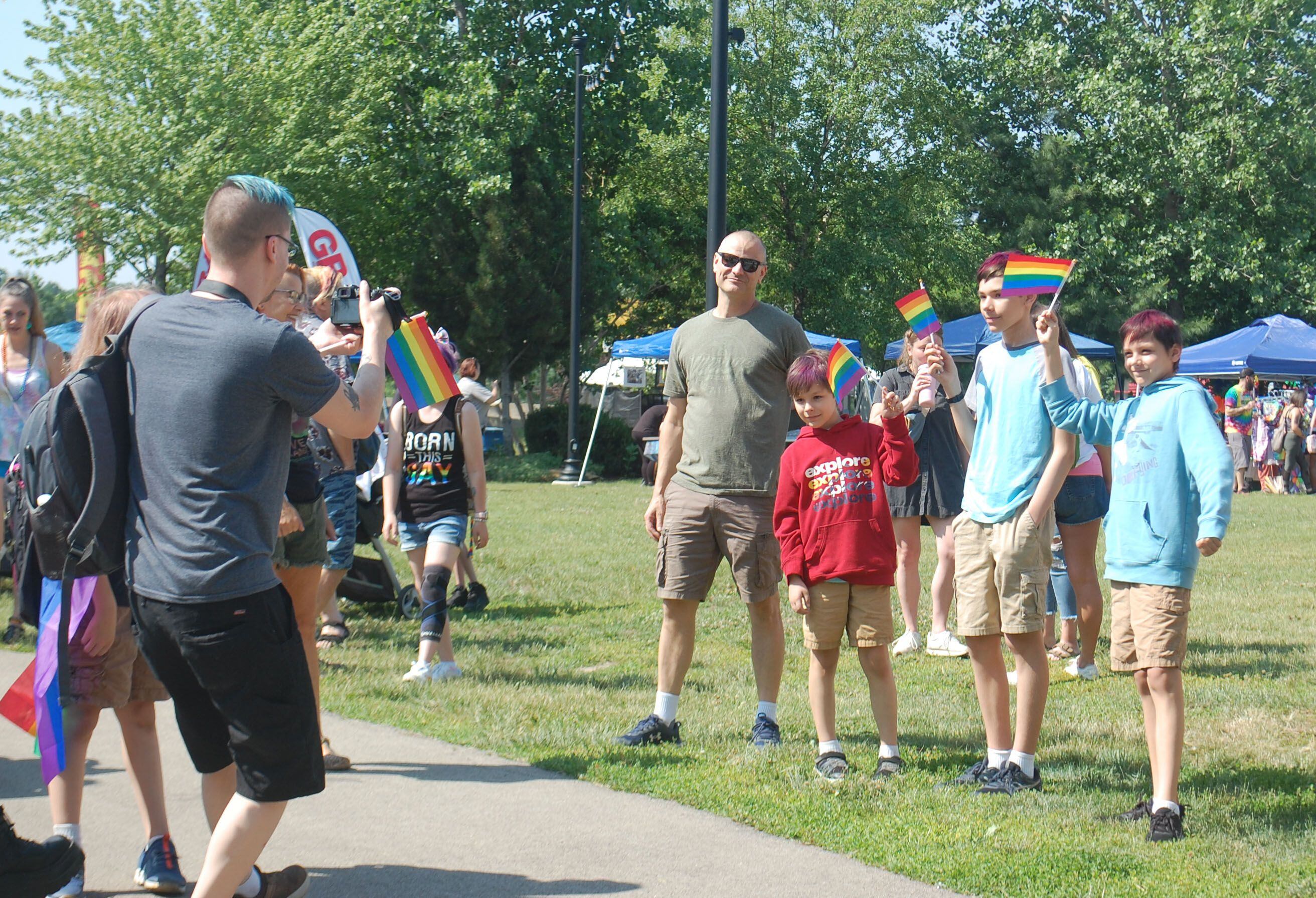 A family poses for a photo with their Pride flags in downtown Ottawa's Jordan block during the Ottawa Family Pride Festival on Saturday, June 10, 2023.