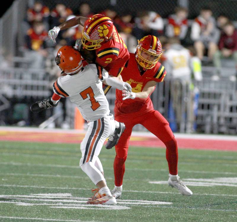 Batavia’s Isaiah Brown carries the ball as he flies over the shoulder of Wheaton Warrenville South’s Brody Faulstich on Friday, Oct. 18, 2024 during a game at Batavia.