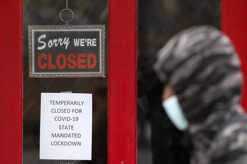 A pedestrian walks by The Framing Gallery, closed due to the COVID-19 pandemic, in Grosse Pointe, Mich., Thursday, May 7, 2020. Michigan Gov. Gretchen Whitmer said Thursday that auto and other manufacturing workers can return to the job next week, further easing her stay-at-home order while extending it through May 28 because of the coronavirus pandemic. (AP Photo/Paul Sancya)