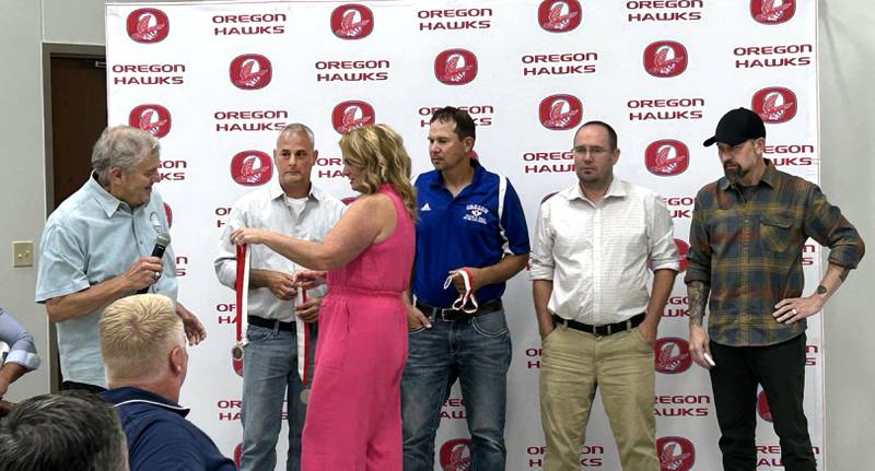 Oregon High School Principal Heidi Deininger presents former track coach Art Carlson (left) and some members of the 1997 boys cross country team, Chad Zellers, Dan Dietrich, Tom Bottoms, and Seth Grennan  with OCUSD Hall of Fame medals during a ceremony on Saturday, Sept. 14, 2024 at the Rock River Center in Oregon. The team won the Class A title n 2007, marking Oregon High School's first state championship.