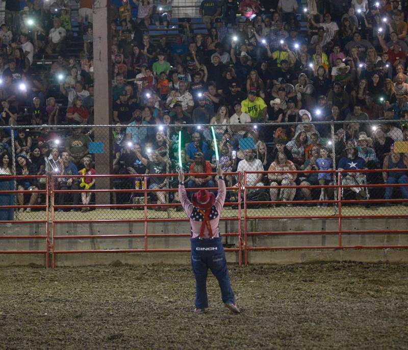 Rodeo clown Trey Casey leads the crowd with a sing-a-long with their phone lights on during a break in the action at the Big Hat Rodeo during the Ogle County Fair on Friday, Aug. 4, 2023.