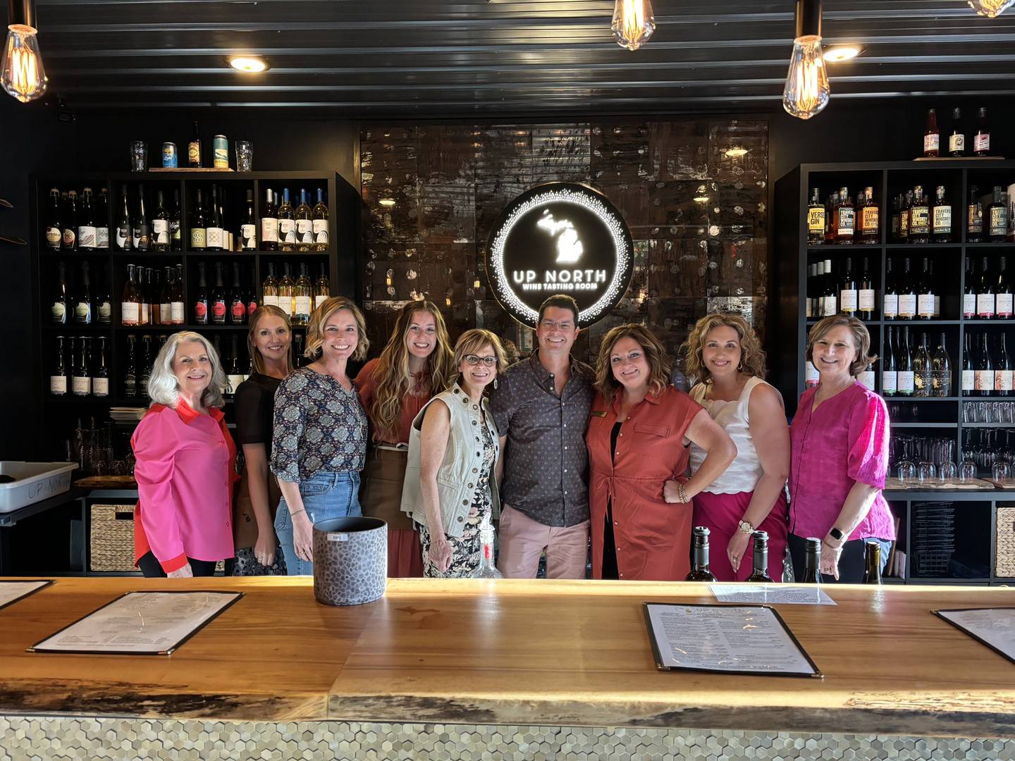 The Up North Wine Tasting Room team beams into the camera, giving a taste of the wine haven's friendly and warm atmosphere.