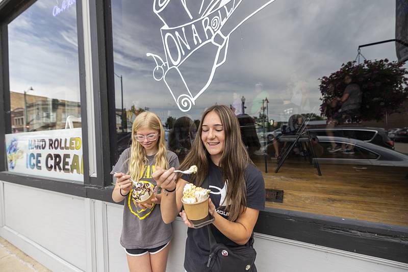 Parker Magne (left), 13, and Taylor Frost-Magne, 14, dig into cups of ice cream Monday, July 1, 2024, outside of new shop On A Roll in Dixon.