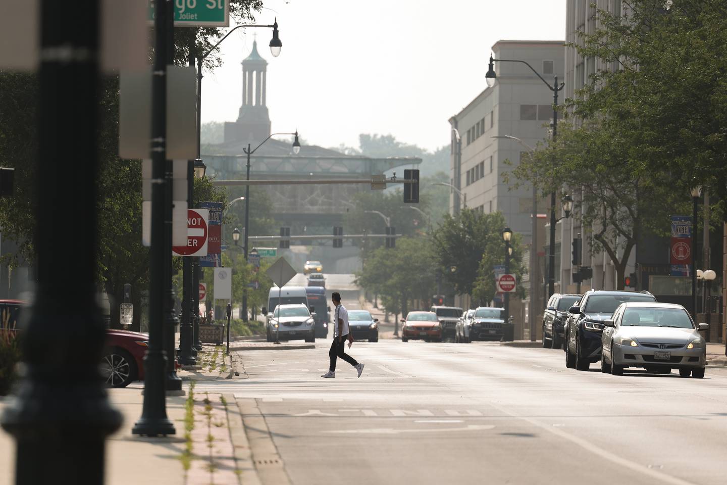 A pedestrian crosses Jefferson Street in Downtown Joliet. Temperatures remain in the low 90’s as the day near an end.