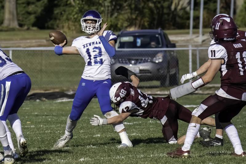 Newman’s JJ Castle gets hit as he throws Saturday, Oct. 29, 2022 during the Comet’s first round playoff game against Rockridge.