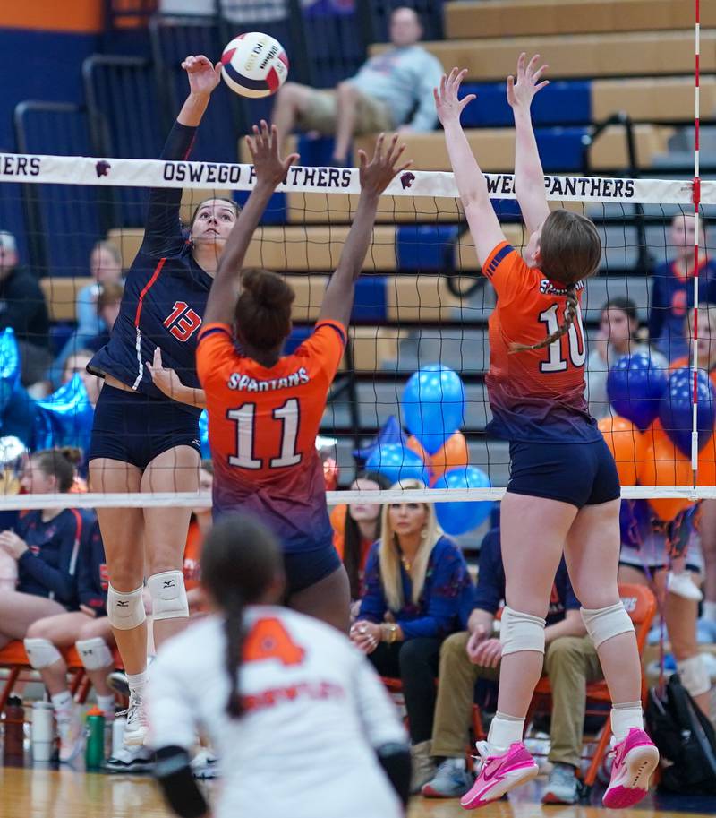 Oswego’s Sidney Hamaker (13) goes up for a kill against Romeoville's Grace Griffin (11) and Kameron Blizniak (10) during a volleyball game at Oswego High School on Tuesday, Oct. 17, 2023.