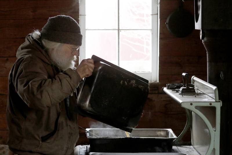 Chuck Howenstine moves cooking maple syrup into another pan on Thursday, March 9, 2023, at the Pioneer Tree Farm near McHenry. He has been collecting sap for most of his adult life to make maple syrup that he gives away.