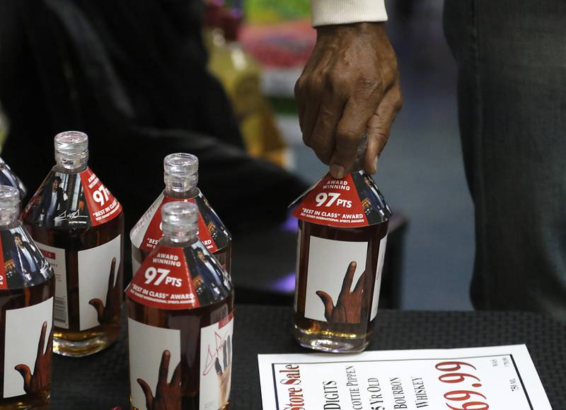 Retired Chicago Bulls star Scottie Pippen grabs a bottle of his Digits bourbon on Thursday, Feb. 9, 2023, at The International House of Wine and Cheese, at 11302 Route 12, in Richmond, before signing it for a customer.