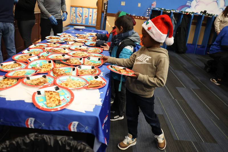 A child takes some pizza at the Boys & Girls Club Joliet pizza party on Saturday, Dec.18, 2023.