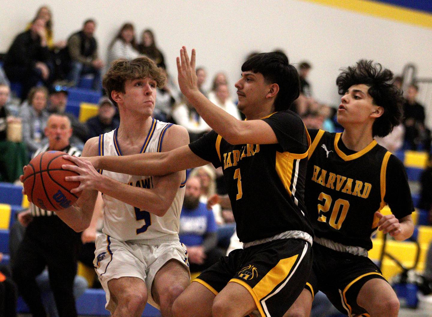 Johnsburg’s Kyle Patterson, left, moves the ball against Harvard’s Joseph Vazquez, center, and Jualian Acosta, right, in varsity boys basketball at Johnsburg Saturday.