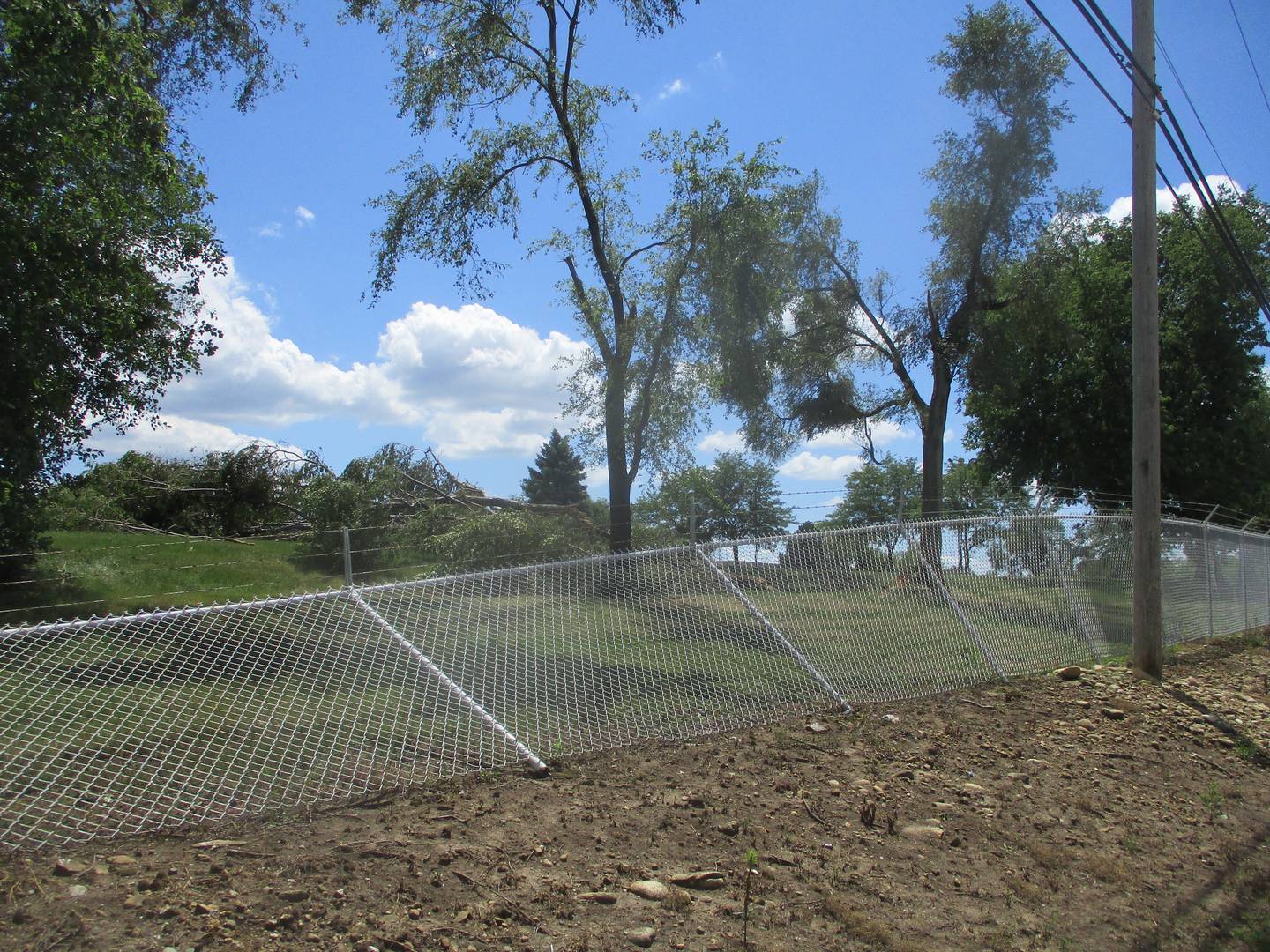 A section of chainlink fence and trees outside the Crane Composite factory along U.S. 6 at the Joliet-Channahon border were knocked down by what the National Weather Service is saying was an EF-1 tornado on Friday night. July 30, 2023.