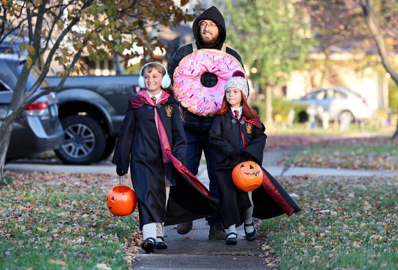 Brian Schwebach and his daughters Nellie, (left) 10, and Lucy, 7, from DeKalb, trick-or-treat on Halloween Tuesday, Oct. 31, 2023, in DeKalb.