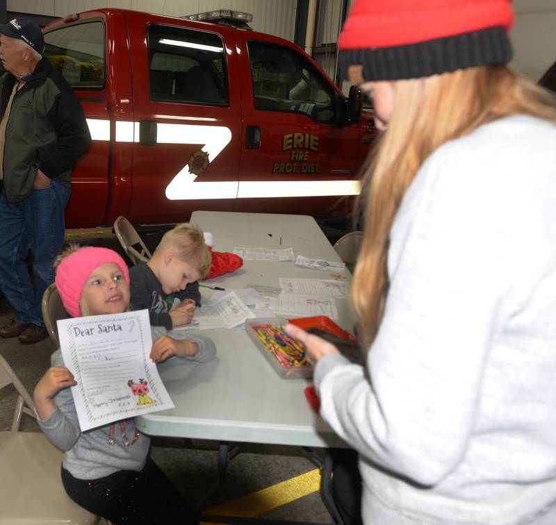 Rosalee Tenbor, 3, of Erie, shows her letter to Santa to her mom Karlie as her brother, Anthony, 4, colors his during Erie's Hometown Holidays on Saturday, Dec. 2, 2023. Letter writing was one of the kids activities offered at the Erie Fire Station.