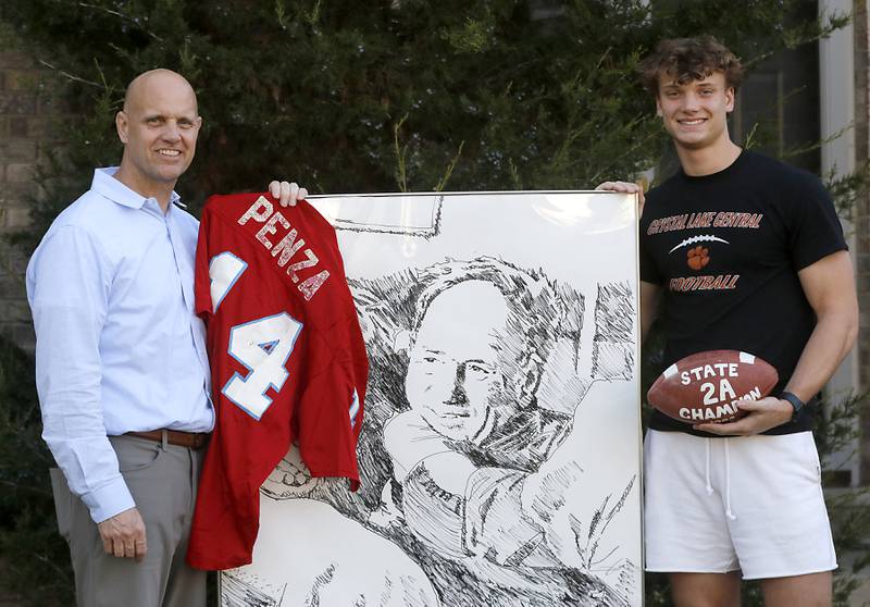 Greg Penza and his son, Crystal Lake Central quarterback Jason Penza, stand with a drawing of Greg's father, and Jason's grandfather, Don Penza, who took Marian Central to state prominence with four state titles in the 1980's.