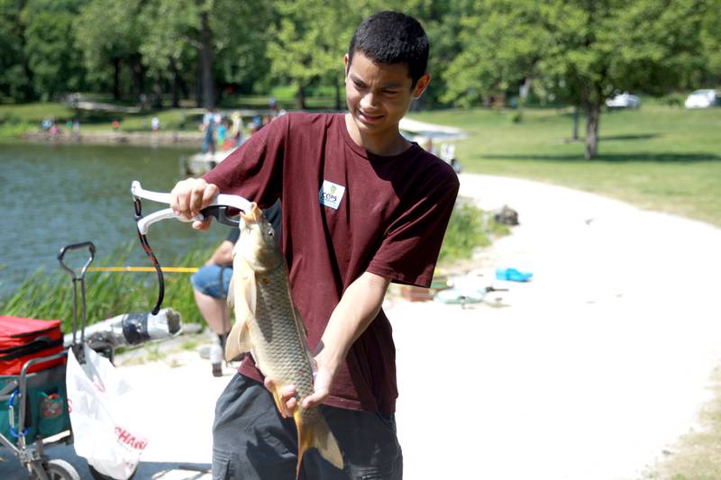 Benjamin Hernandez, 15, shows off the carp he caught at Herrick Lake Forest Preserve during the DuPage Forest Preserve Police Cops and Bobbers event in Wheaton on Wednesday, June 19, 2024.