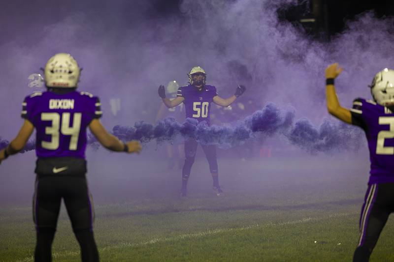 A purple haze hangs over A.C. Bowers Field as Dixon’s Aidan Howard leads his team in warm-ups Friday, Oct. 18, 2024. Excitement is high as the Dukes put their unblemished record on the line against the Byron Tiger’s own 7-0 record. Winner will take the Big Northern Conference championship.