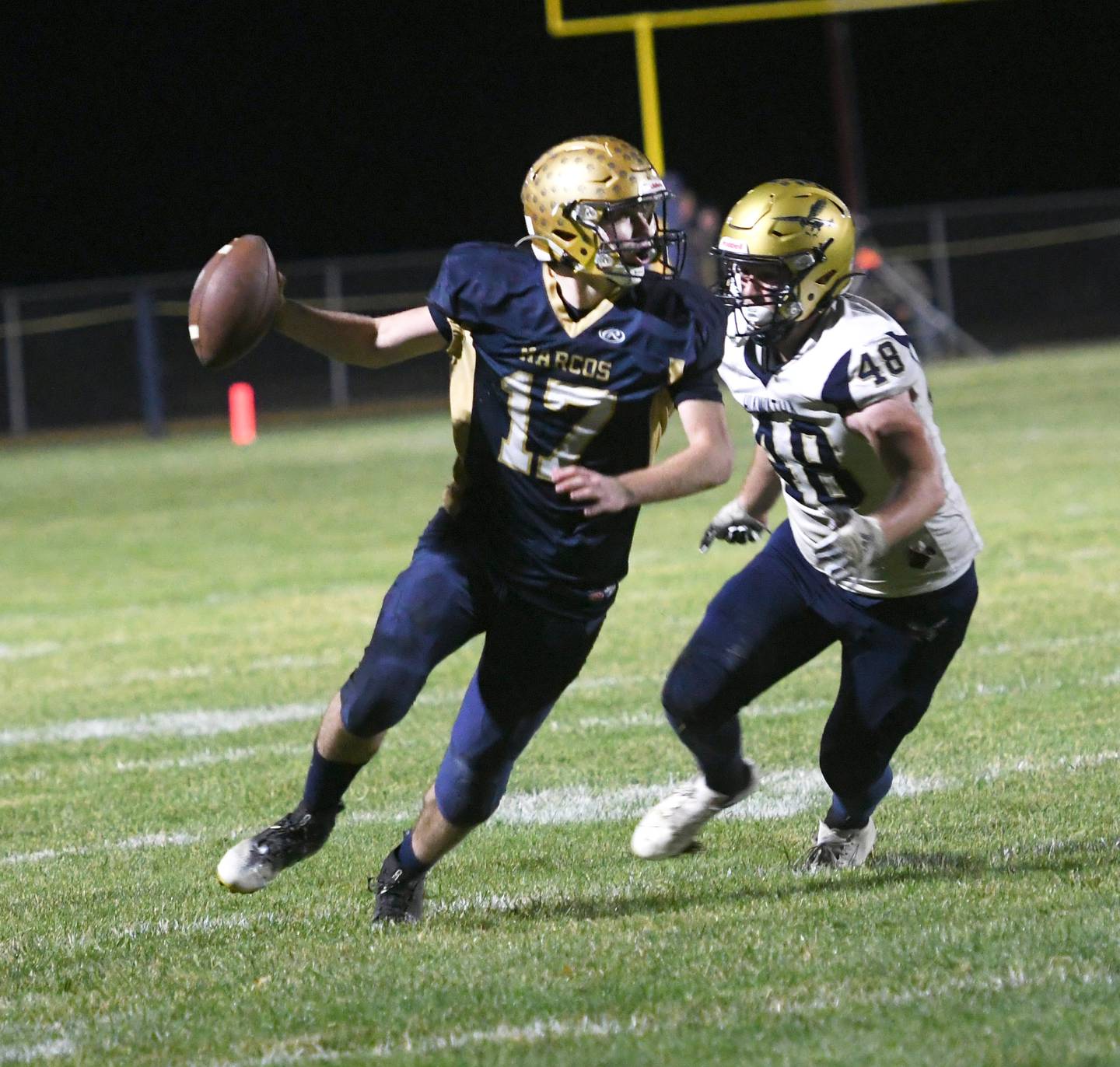 Polo's Brock Soltow scrambles out of the pocket to avoid Hiawatha's Zachary Edwards during 8-man playoff action on Friday. Oct. 28.