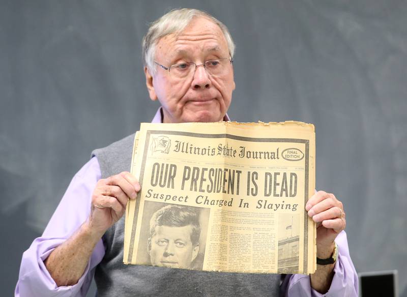 Heinz Suppan former teacher at Marquette High School holds a Illinios State Journal newspaper while giving a presentation to a class about his remembrance of the President John F. Kennedy assassination on Thursday, Nov. 16, 2023 at Marquette High School. This year marks the 60th anniversary of the Kennedy assassination.
