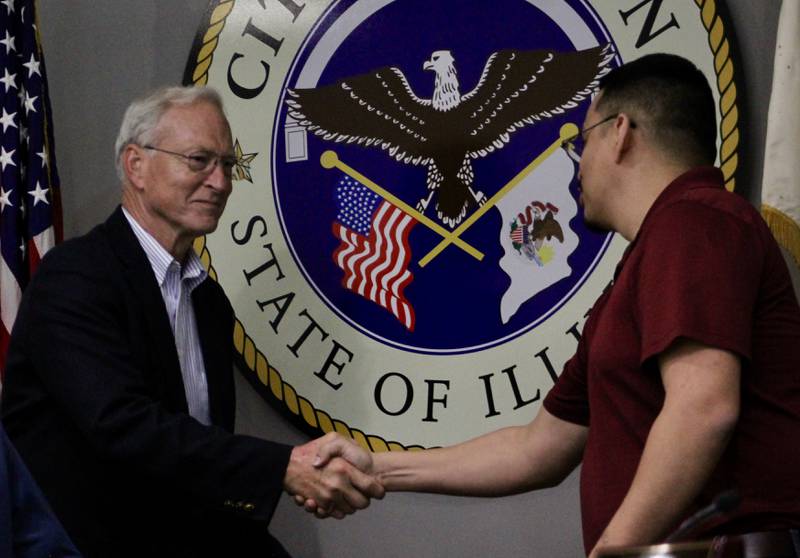 Newly sworn-in Mayor Glen Hughes accepts a handshake from his predecessor Li Arellano Jr. on Monday, May 1, 2023.