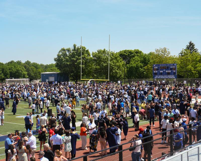 Families and friends gather on the football field after graduation at Downers Grove South High School held on Sunday May 19, 2024.