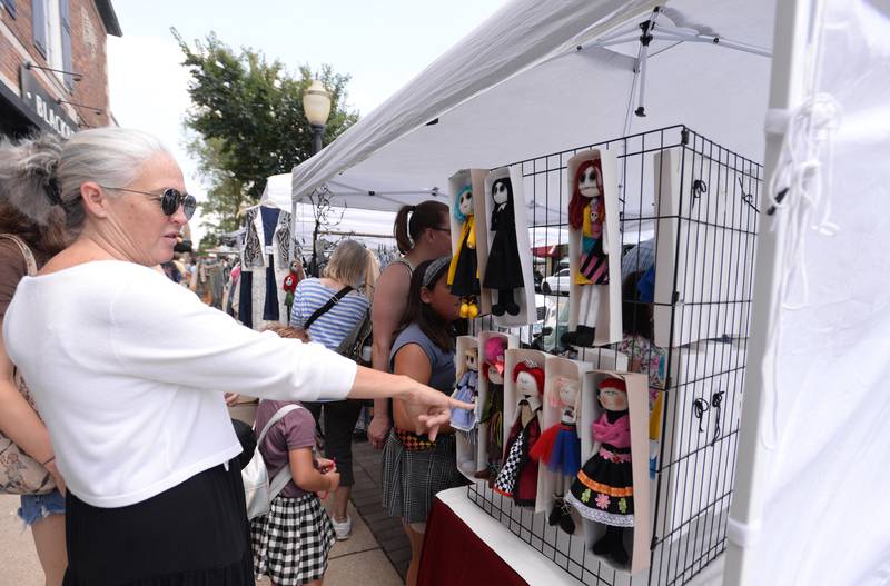 Stephanie Beck of LaGrange admires some of the Freaky Merlina dolls at the LaGrange Craft Fair held Saturday, July 13, 2024.