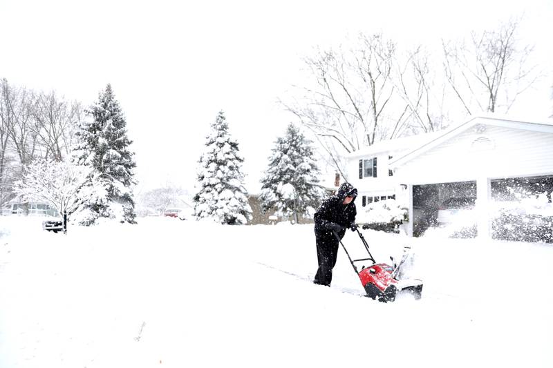 Mike Brown clears the sidewalk outside his Batavia home following several more inches of snowfall in Kane County on Friday, Jan. 12, 2024.