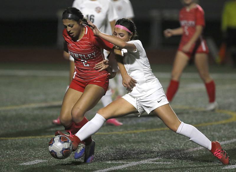 McHenry's Elena Carlos kicks the ball away from Huntley’s Gabi Farraj during a Fox Valley Conference soccer match Thursday, April 13, 2023, at Huntley High School.