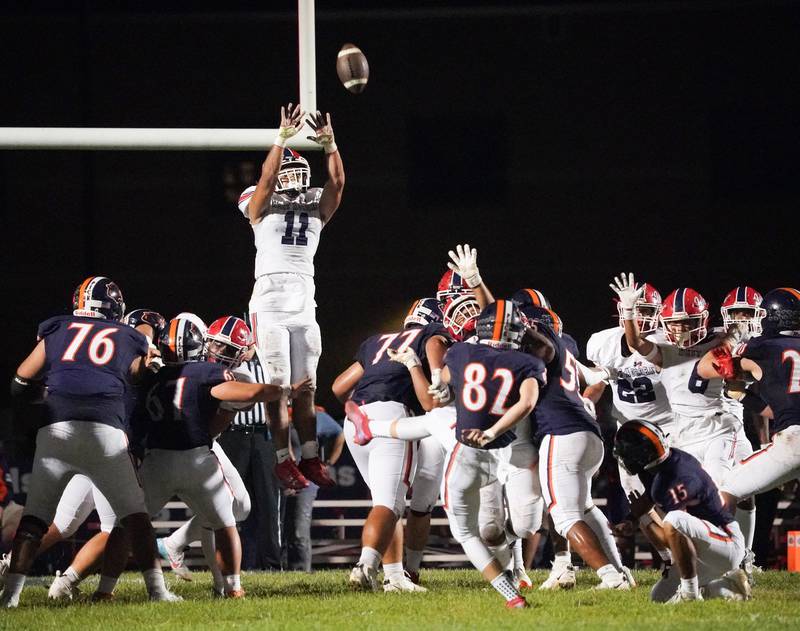 West Aurora's Luis Estrella (11) leaps to defend against an extra point attempt by Oswego’s Tanner Stumpenhorst (82) during a football game at Oswego High School on Friday, Sept. 29, 2023.