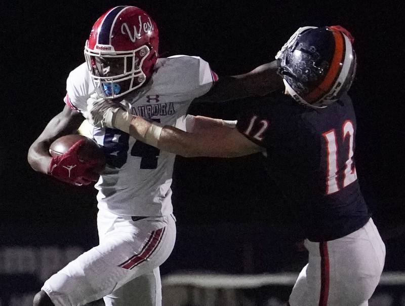 West Aurora's Kewon Marshall (84) stiff arms Oswego’s Patrick OToole (12) after the catch during a football game at Oswego High School on Friday, Sept. 29, 2023.