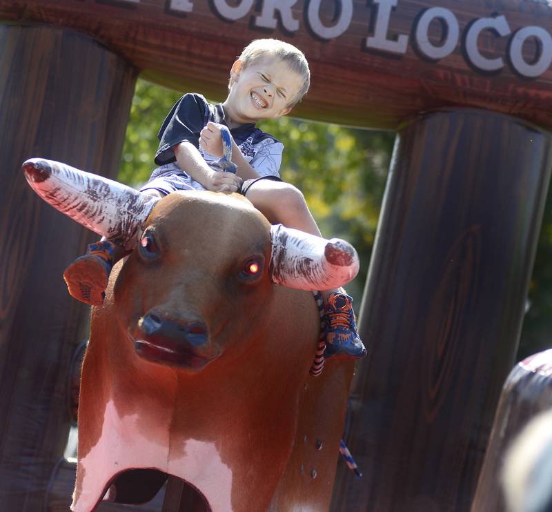 Hanging on the best he can, Elijah Zoelzer takes a ride on a mechanical bull Saturday during the annual Scarecrow Festival in Ottawa.