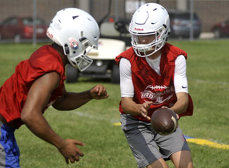 Dundee-Crown quarterback Evan Echlin hands the ball off to running back Davontae Harvey  during football practice July 8 in Carpentersville. The Chargers are coming off a 4-5 season, their best finish since 2013.