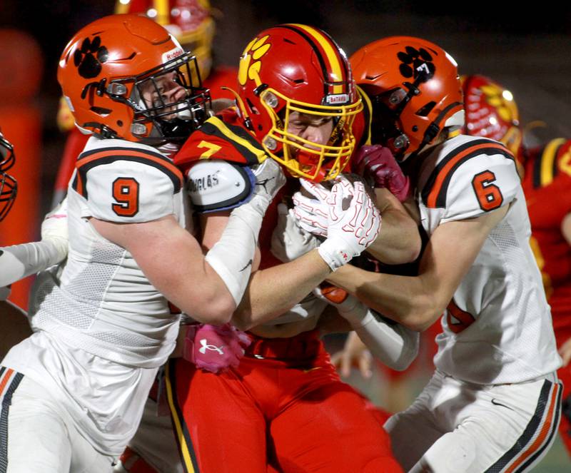 Batavia’s Greyson Kelly (center) is wrapped up by Wheaton Warrenville South defenders Kirby Christensen (left) and Colin Cahill (right) on Friday, Oct. 18, 2024 during a game at Batavia.