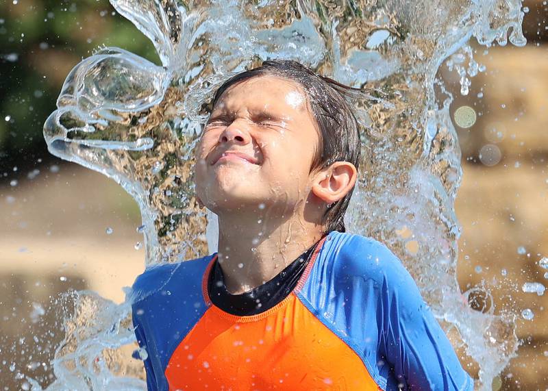 David Swanson, 8, who is in Sycamore visiting his grandparents from Madison Wis., is dumped on by a bucket of water Wednesday, Aug. 23, 2023, at the Sycamore Park District Splash Fountain splash pad. Temperatures climbed into the high 90’s Wednesday with more hot weather expected Thursday.